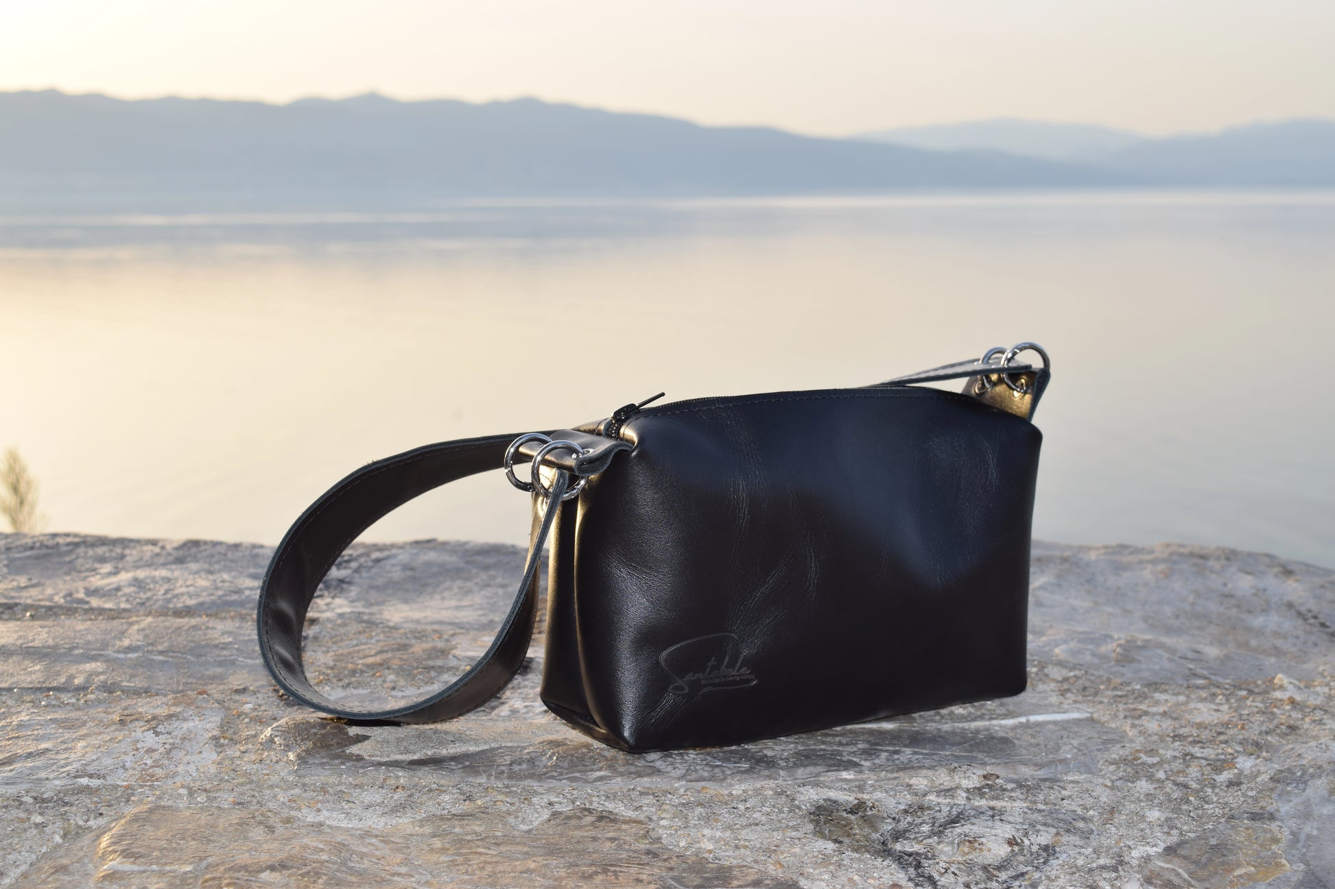 Elegant wide-strap handbag in premium black Italian goat leather, featuring four silver O-rings, connecting O-ring, black zipper closure, and meticulous black stitching — timeless luxury by Santebela.