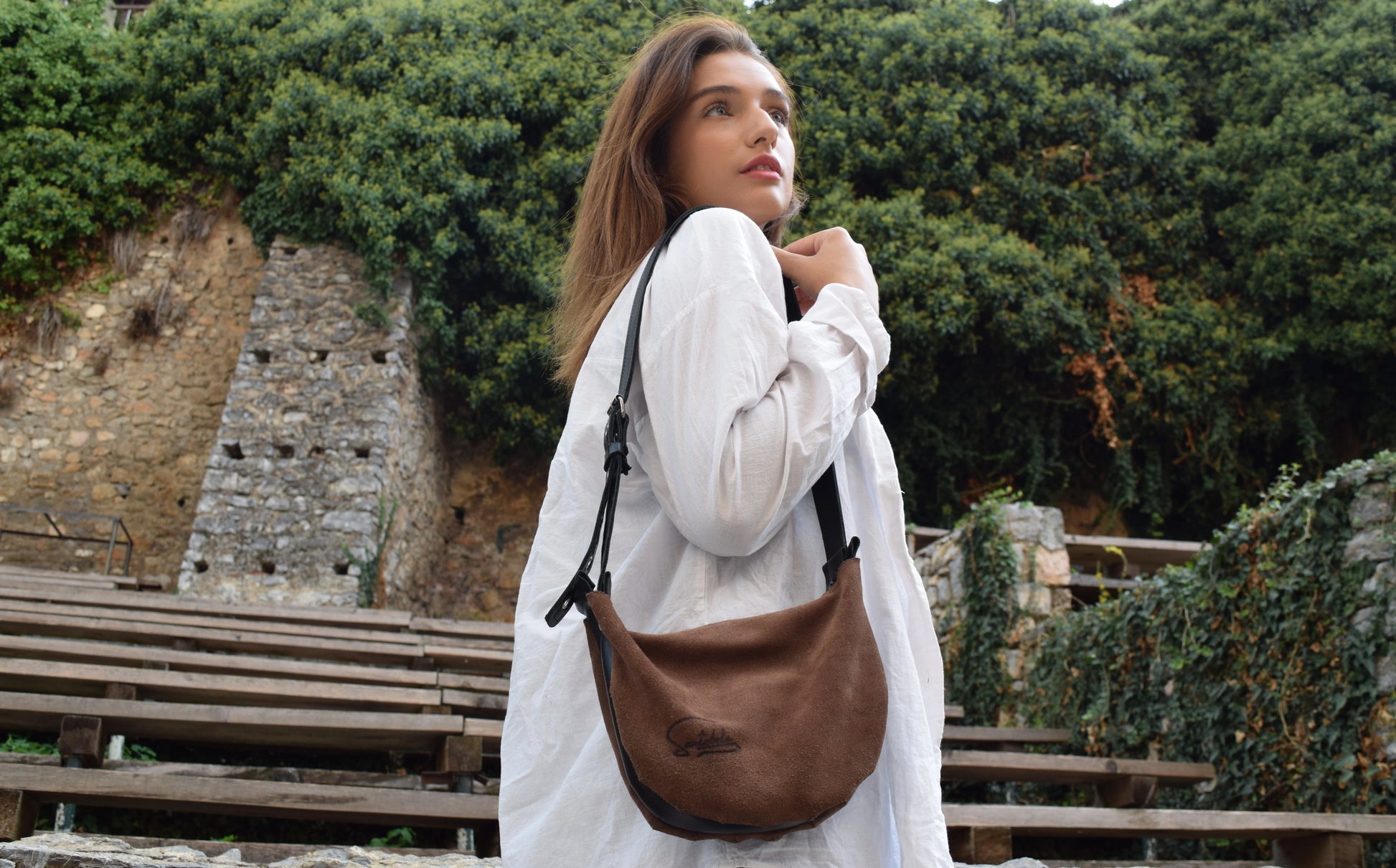 Minimalistic luxury crossbody brown bag presented by the model on the stairs from the workshop to you by Santebela