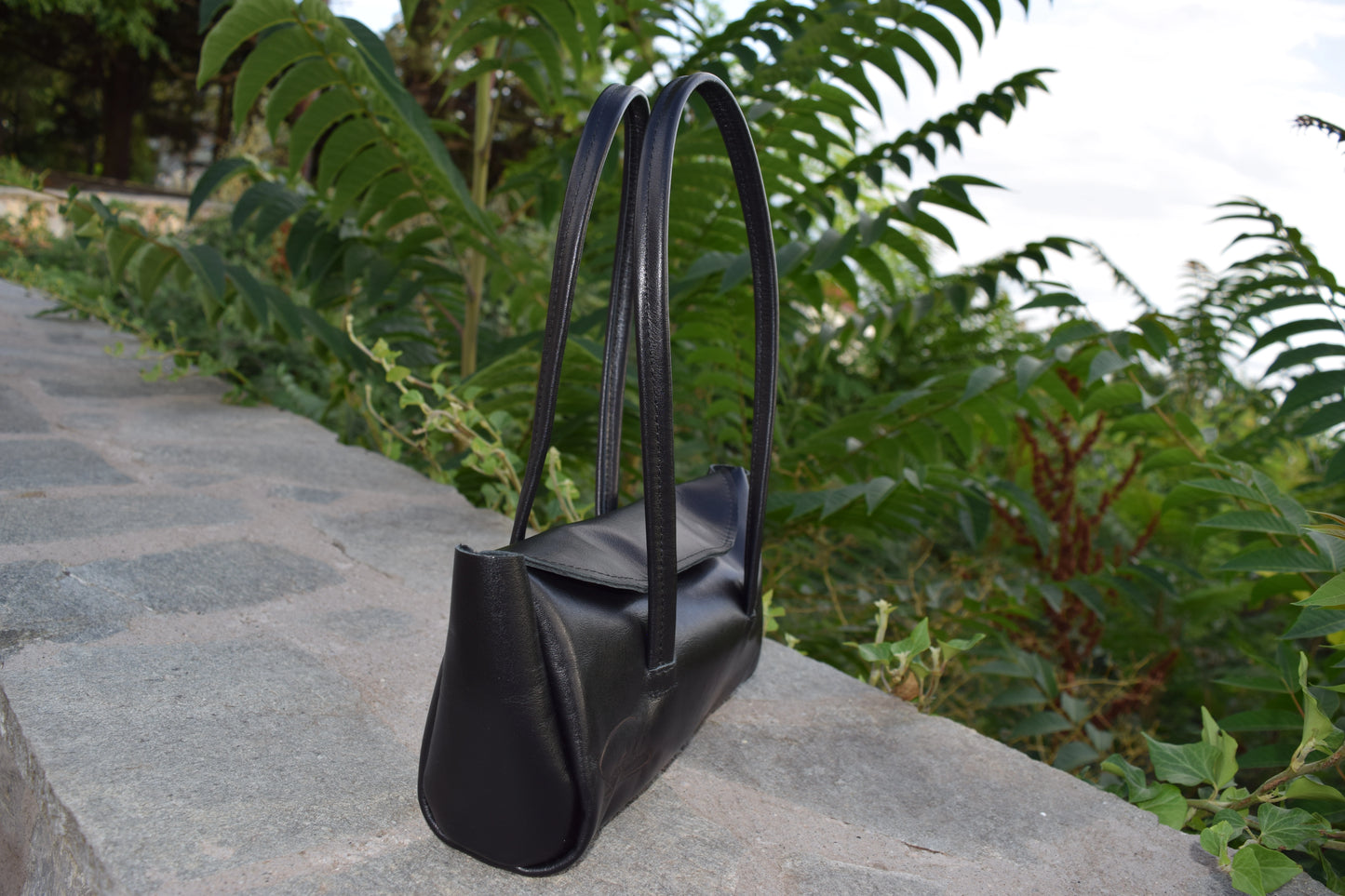 Side view of Fiera Black Italian Goat Leather Handbag, showing smooth leather and the side details precisely crafted by Santebela