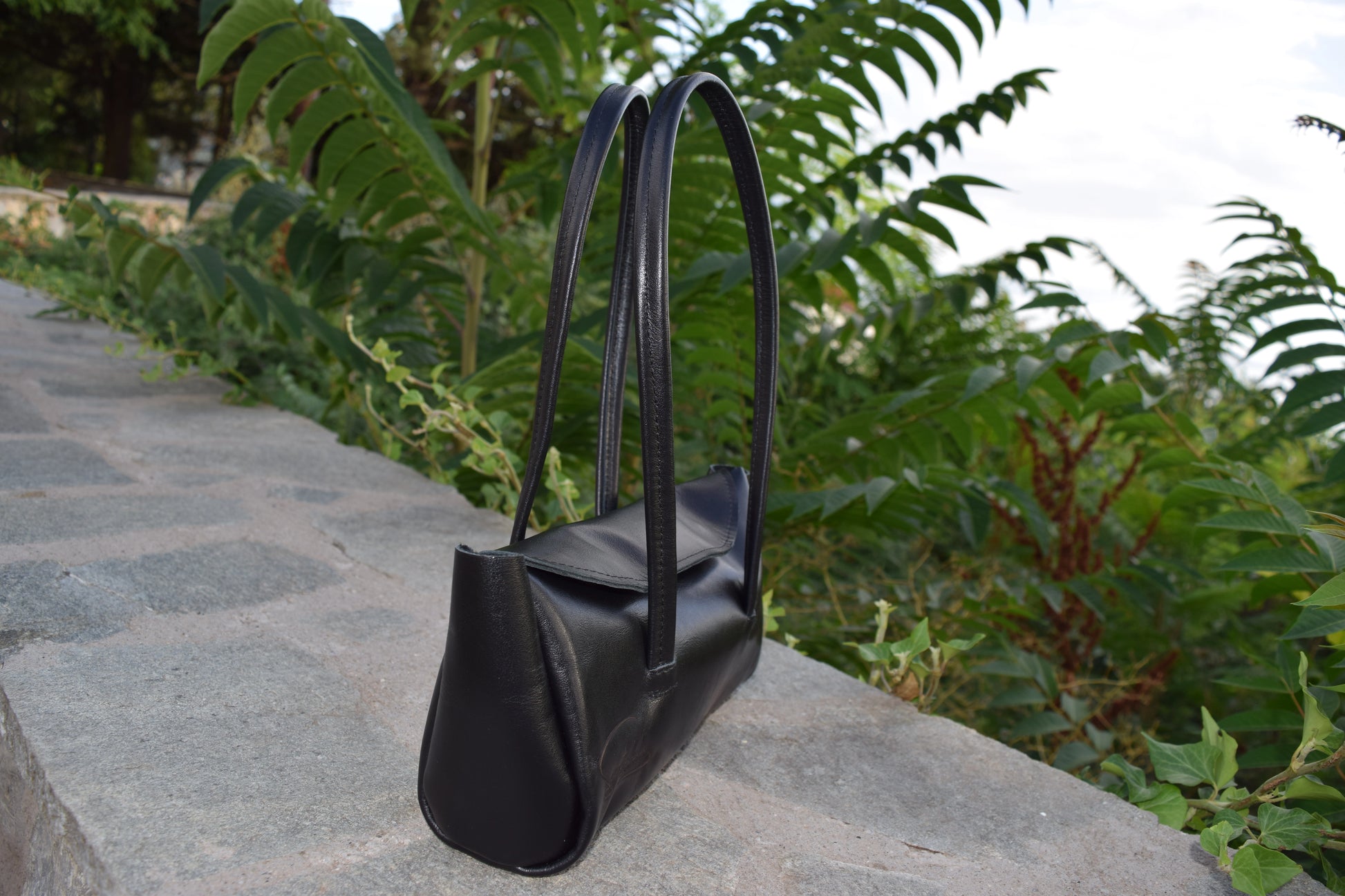 Side view of Fiera Black Italian Goat Leather Handbag, showing smooth leather and the side details precisely crafted by Santebela