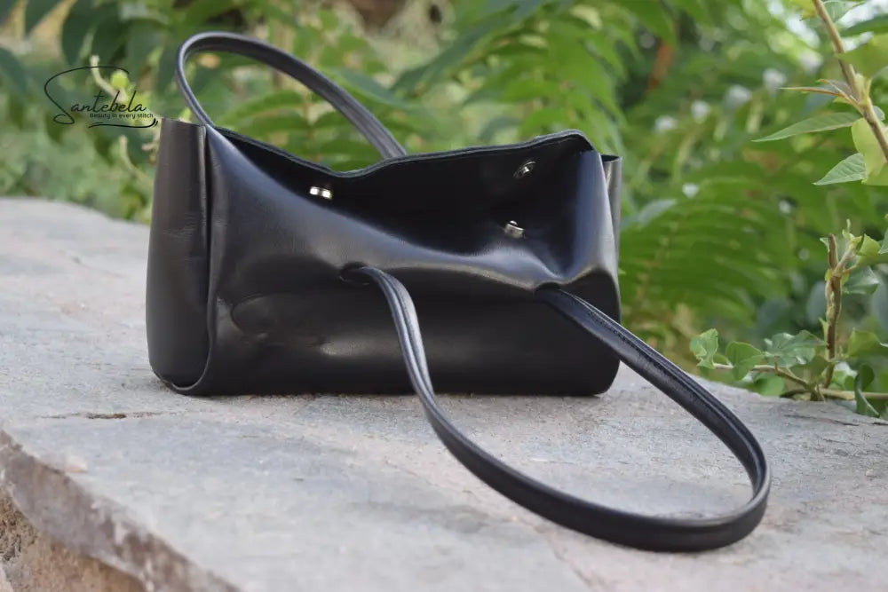Partly open view of the Fiera Black Italian Goat Leather Handbag by Santebela, highlighting sturdy handles, silver magnetic closure, and luxurious handmade craftsmanship