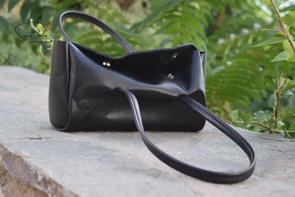 Partly open view of the Fiera Black Italian Goat Leather Handbag by Santebela, highlighting sturdy handles, silver magnetic closure, and luxurious handmade craftsmanship